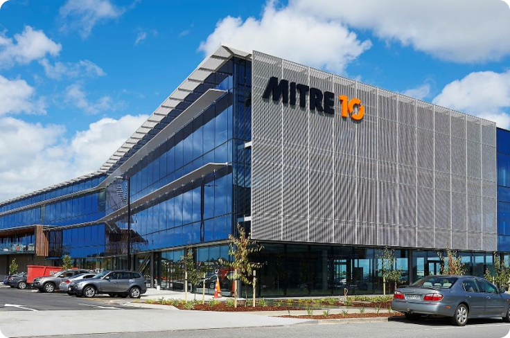 Photography of the Mitre 10 building; it is a facility with modern architecure, three stories tall, with reflective tall windows.
